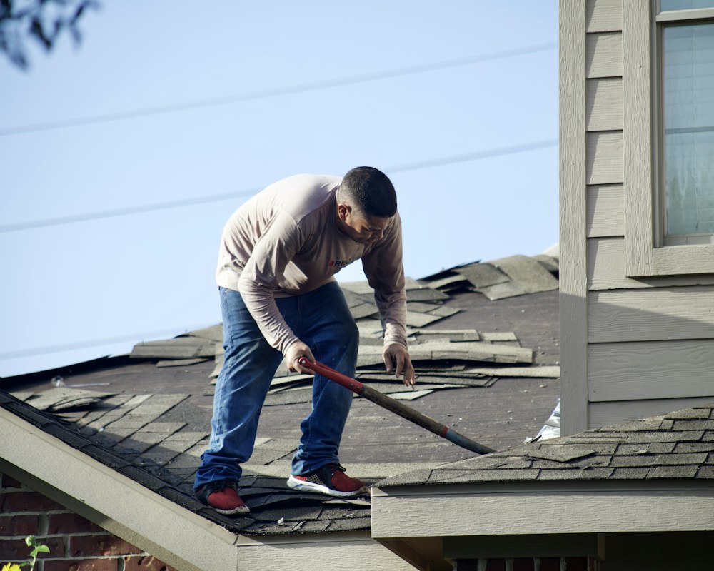 Roofer removing damaged shingles